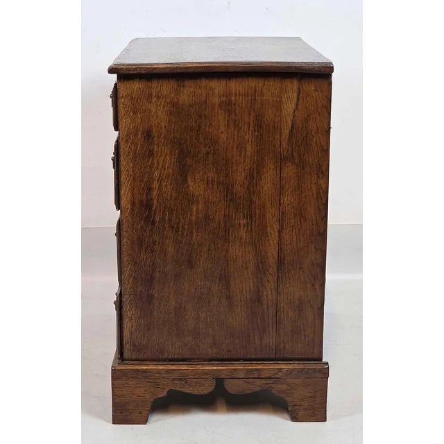 A handsome pair of English oak bedside chests dating to the early 20th century, offering timeless craftsmanship and...