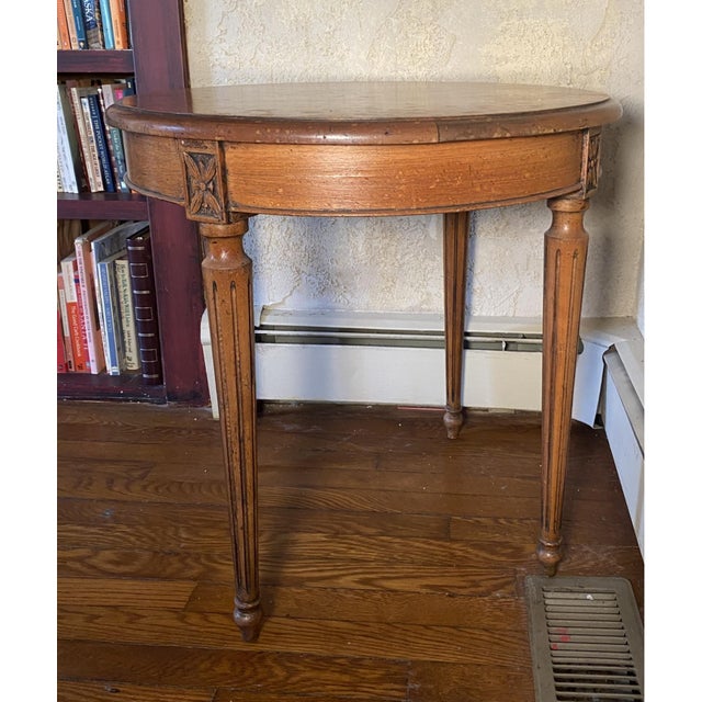 A vintage Fruitwood round side table with a single drawer, brass pull, folate carved apron and turned fluted legs. Product...