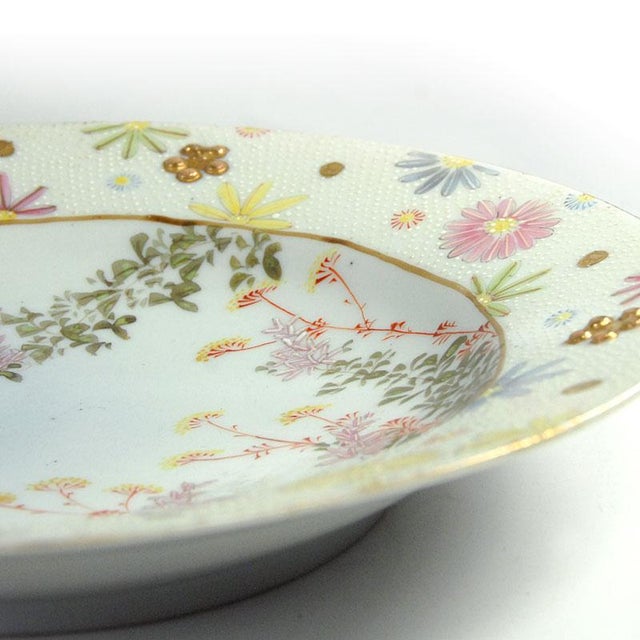 This striking, decorative plate is made of fine porcelain. It is decorated with hand-painted floral ornamentation,...