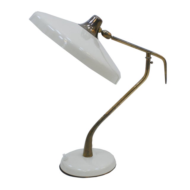 - Mid-Century table lamp - Designed by Oscar Torlasco for Lumi - Features a curved brass structure - White lacquered steel...