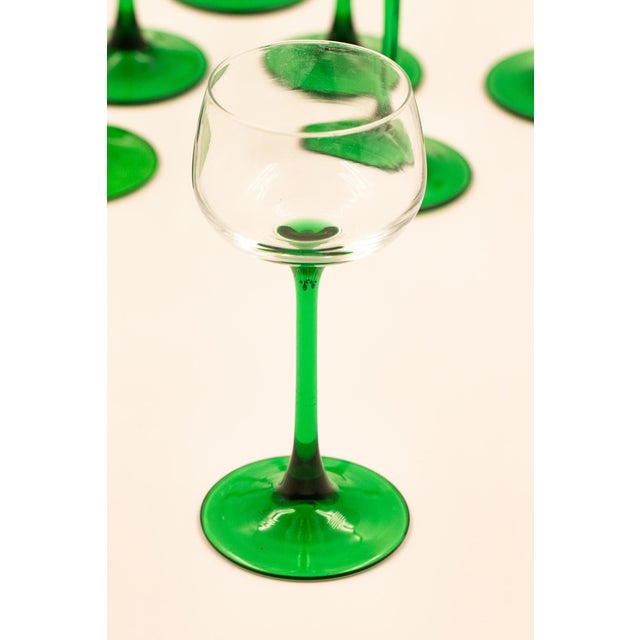 Clear tulip-shaped bowls on tall, slender emerald green stems with a flat circular base. The green is consistent and...