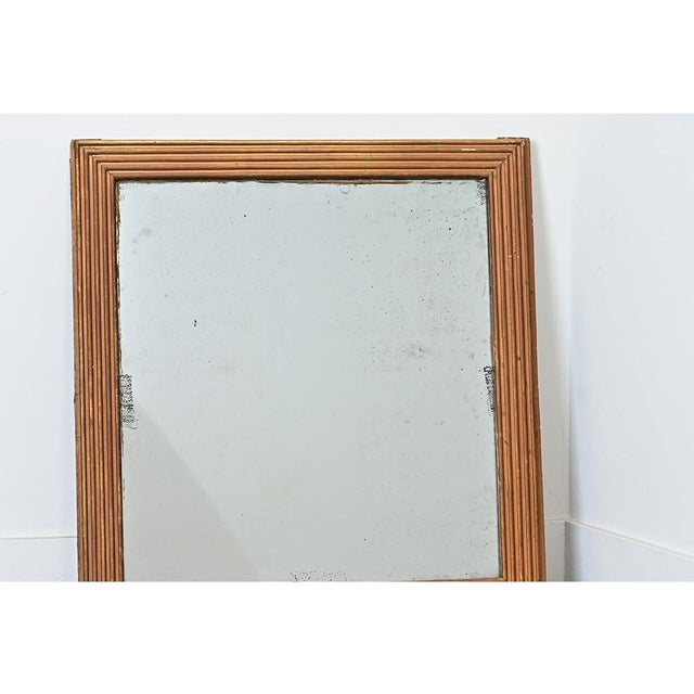 A French mirror from circa 1840, framed in classic reeded molding of the Louis XVI taste that reflects the luster of gold,...