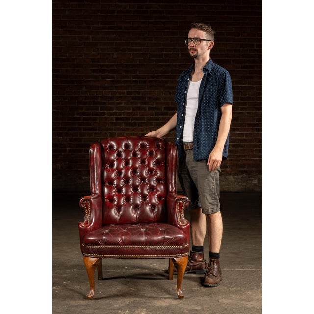 Handsome tufted leather armchair upholstered in deep oxblood leather, with button-tufting across the high back and seat....