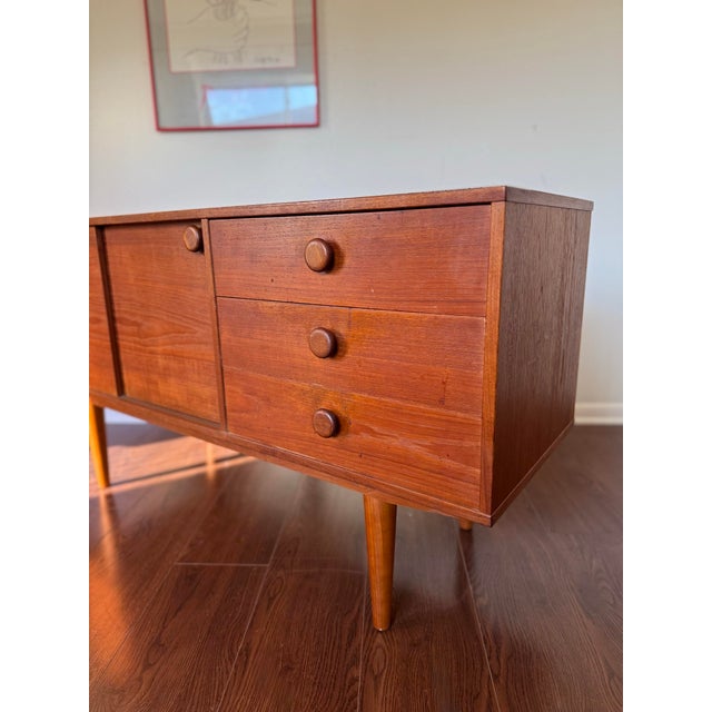 Cute petite mid century modern teak sideboard with round pulls, circa 1960s. Features smooth sliding doors, round...