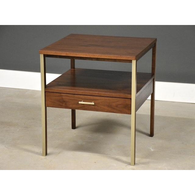 A mid century modern walnut and light brass colored aluminum nightstand designed by Paul McCobb for Calvin Collection....