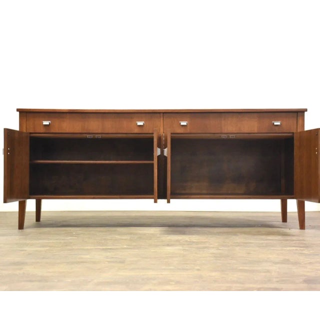 A mid century modern walnut credenza with a black formica scratch resistant top and aluminum pulls. Professionally...