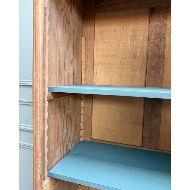 With its sculpted arched pediment, small-paned glass door, and stylized geometric ornaments, this small display cabinet...