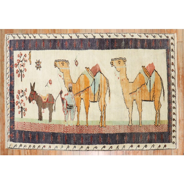 Mid-20th century colrufl Turkish rug depicting camel and donkeys on an ivory ground. Size: 3'5'' x 5'3''.