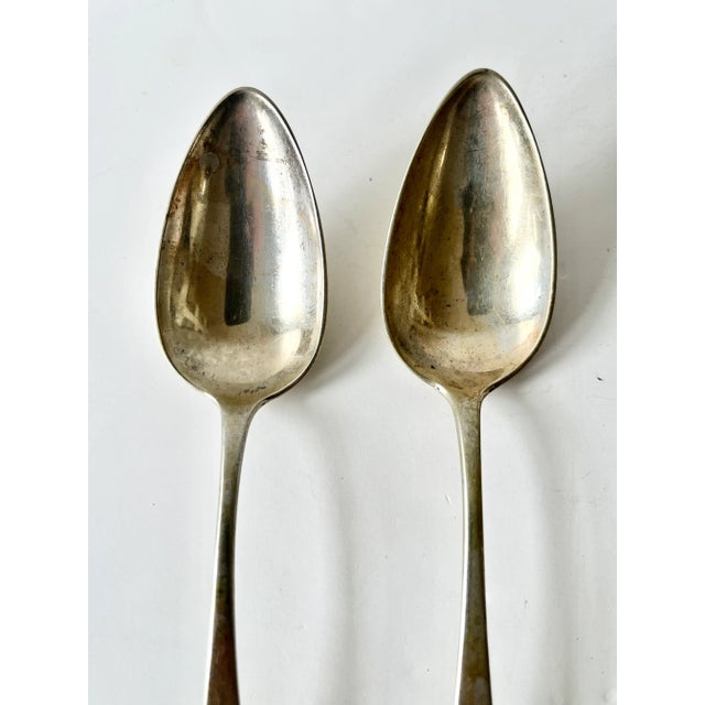 A pair of early 19th century coin silver spoons. Each features a long and deep bowl with curved handle which is monogramed...