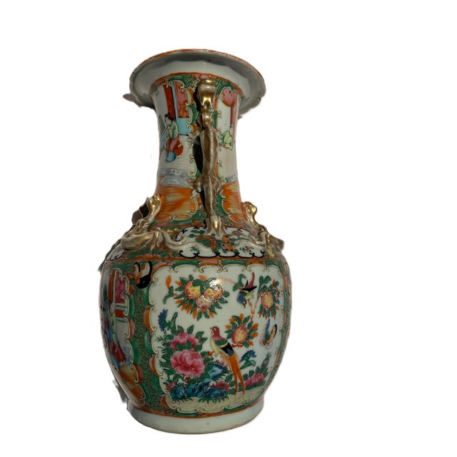A richly decorated Chinese export porcelain vase featuring multi‑scene figural panels, raised gilt accents, and sculpted...