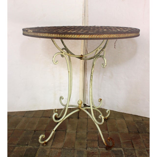 Early 20th century wrought iron bistro table. The top a woven basketry design; the apron tightly woven "reeds"; all...