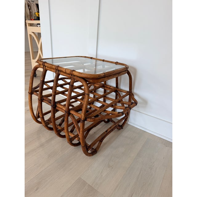 Vintage bent rattan side table featuring a smoked glass top and an airy curved frame. Its timeless design complements...