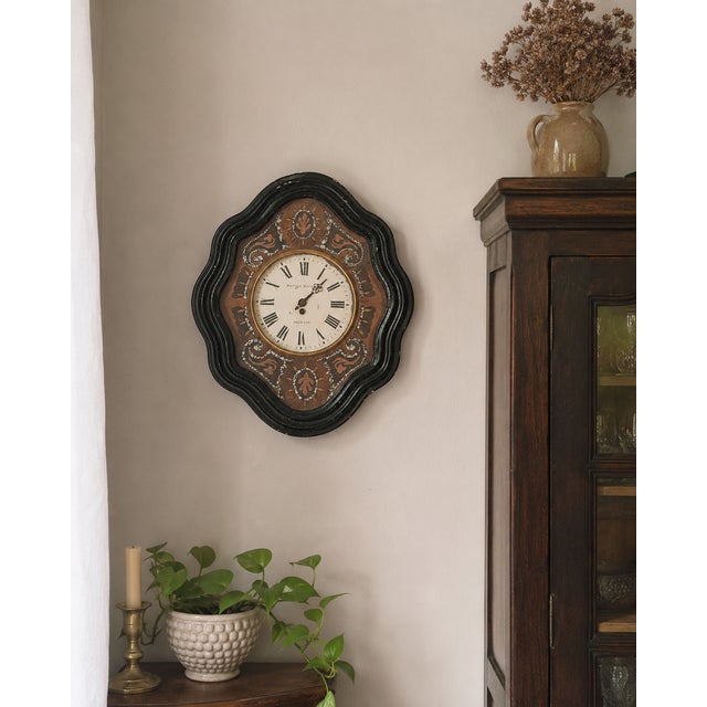 A striking 19th-century French cartel wall clock featuring an elegant shaped ebonized wood case with hand-inlaid mother-...