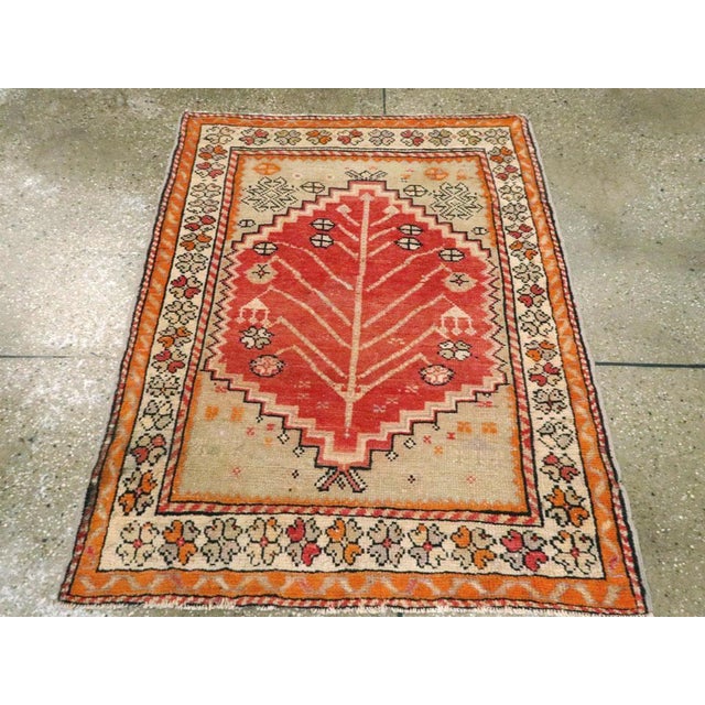 A vintage Turkish Anatolian throw rug. From the Bergama area in northwest Turkey, a coral red field displays a vigorous...