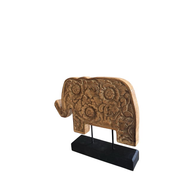Maker unknown. A charming hand-carved wooden elephant sculpture featuring an intricately detailed floral and foliate...