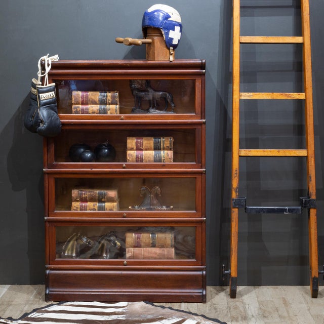 ABOUT A late 19th c. modular 4 stack lawyer's bookcase with brass knobs, brass plated metal straps and glass doors that...