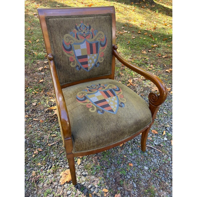 A pair of French Empire style Arm chairs upholstered in an olive velvet emblazoned with heraldic crests on the seats and...