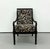 A dramatic vintage armchair featuring a glossy ebonized wood frame with gracefully curved arms, turned front legs, and a...