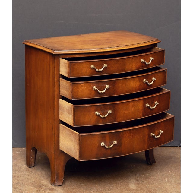 A handsome English bow-fronted small chest of mahogany from the Edwardian era, featuring a moulded top over a frieze of...