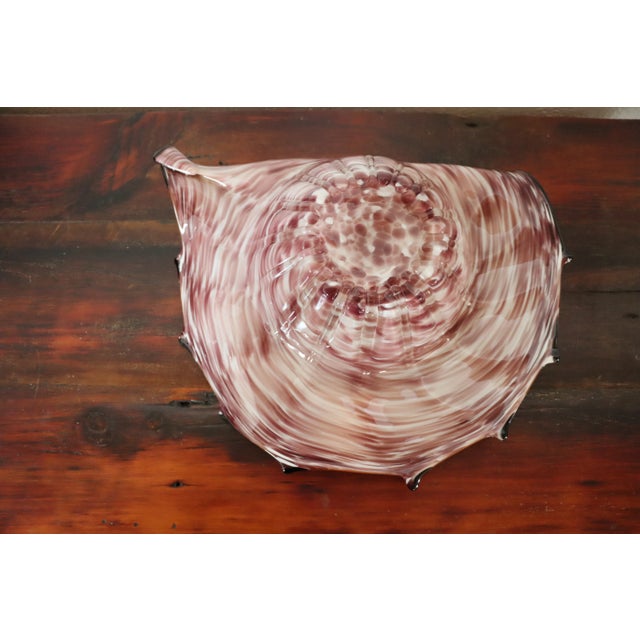 Decorative art glass bowl in purple/burgundy color with mustard and black colored accents.