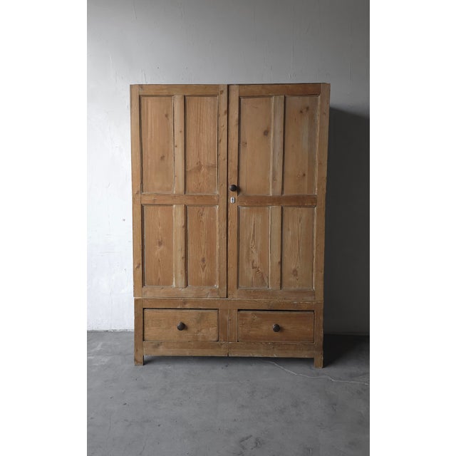This is a 19th Century, rustic European two-door cabinet crafted from solid English pine. Rich in character, the worn...
