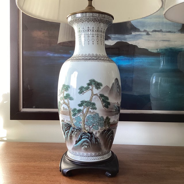 A striking and elegant pair of chinoiserie porcelain table lamps, beautifully decorated with hand-painted scenic...