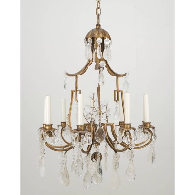 French style chandelier with a gold leaf wrought iron frame, rock crystal teardrops and crystal rosettes and leaves. The...