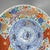 A brightly colored large charger. Japanese porcelain charger, c. 1850. The border is decorated with large gilt Japanese...