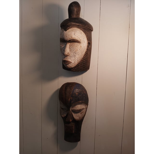 Striking and visually commanding pair of vintage hand carved African masks displaying stylistic influences associated with...