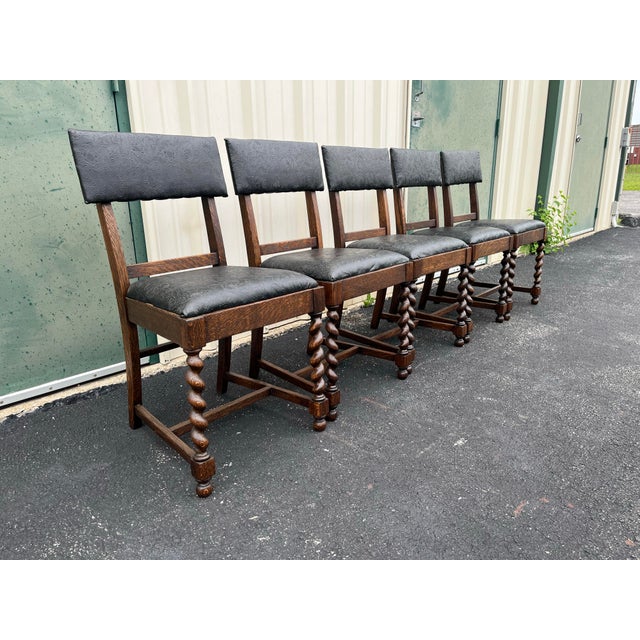 A set of five dark oak barley twist dining chairs from the early 20th century. Each features the classic twisted design on...