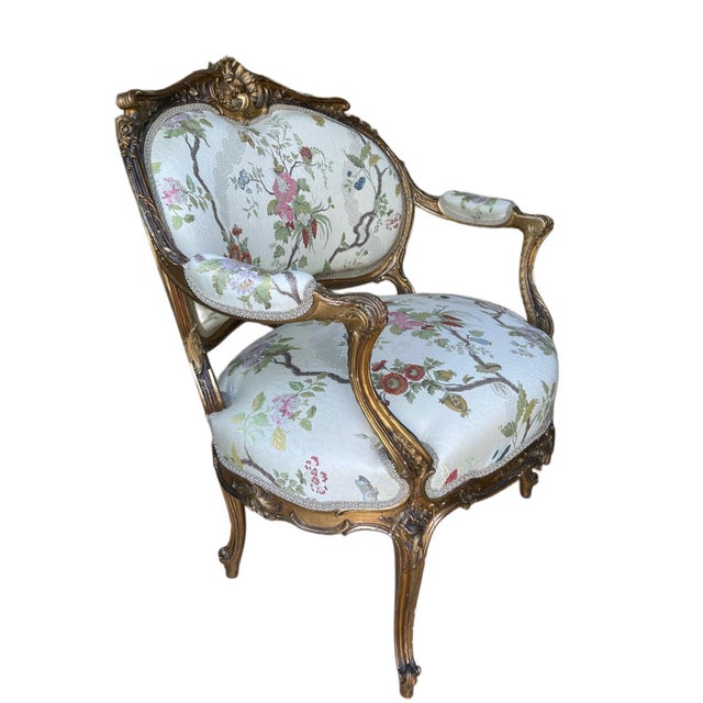 A French marquise armchair dating to circa 1900, hand-carved in giltwood with scrolling foliage and shell motifs typical...