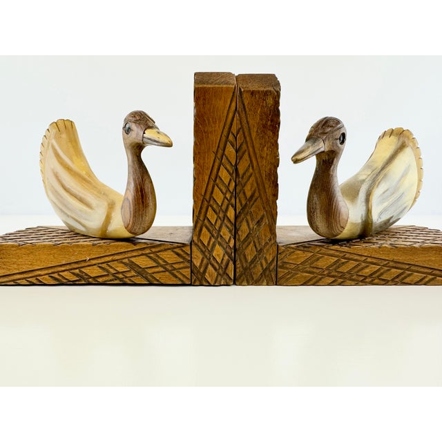 An unique pair of vintage bird bookends combining richly grained carved wooden heads with gracefully curved bodies in a...