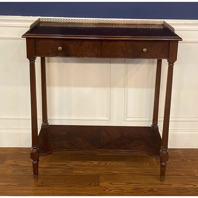 This is a mahogany hall console table by Leighton Hall. It has a brass gallery and a dovetailed drawer with brass pulls....