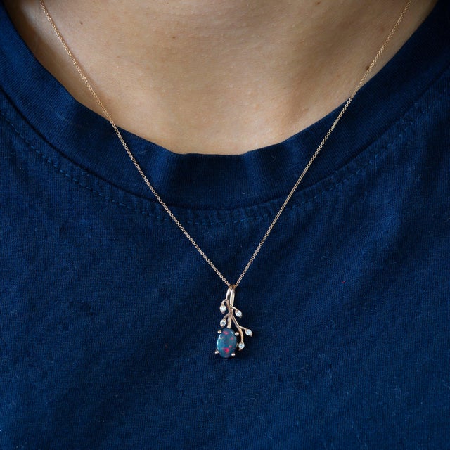 A 1.01-carat black opal cabochon sits at the centre of this solid 14K rose gold pendant, framed by five earth-mined...