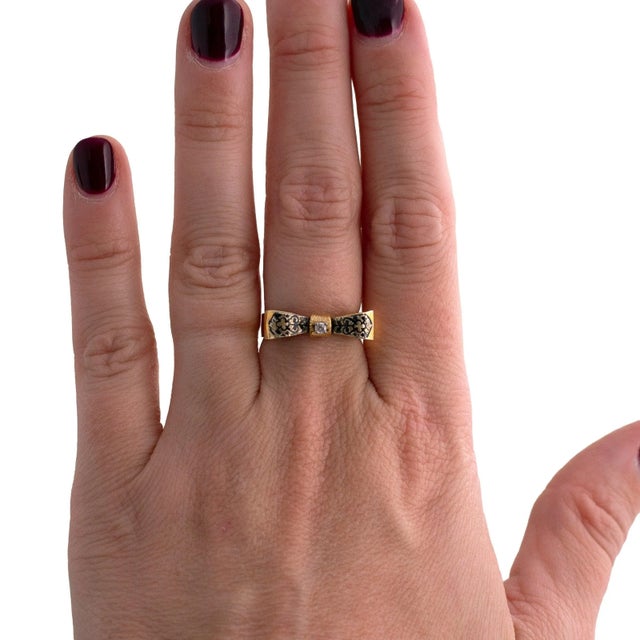 A 14k yellow gold ring with a central white diamond. The design features intricate enamel detailing. The ring size is 6.5...