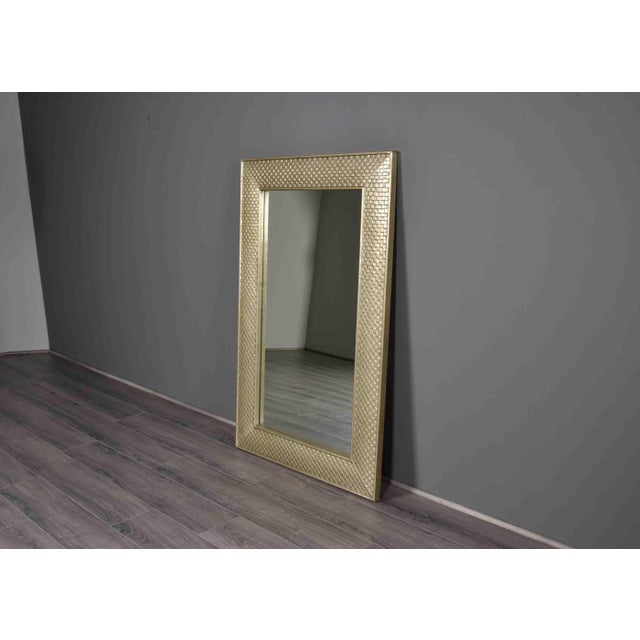 A large rectangular mirror set in a wide frame clad in stamped tin, pressed with an alternating pattern of raised and...