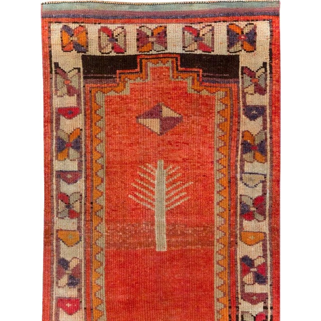 This mid-20th-century Turkish Anatolian runner presents a bold pictorial composition across a rich brick-red field. A...