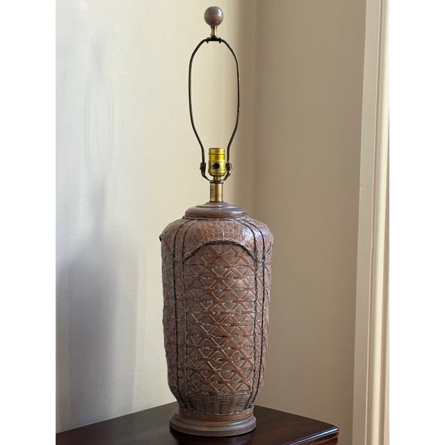 A gorgeous circa 1970 rattan table lamp. An exquisite weave on this fine lamp, which sits atop an elegant wood base. A...