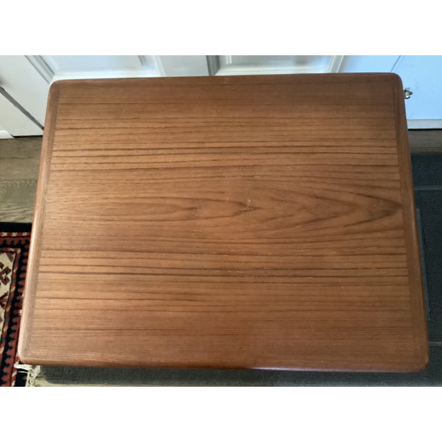 The pair of teak nesting tables was made In Denmark, as noted on the underside of the smaller table. The wood grain is...