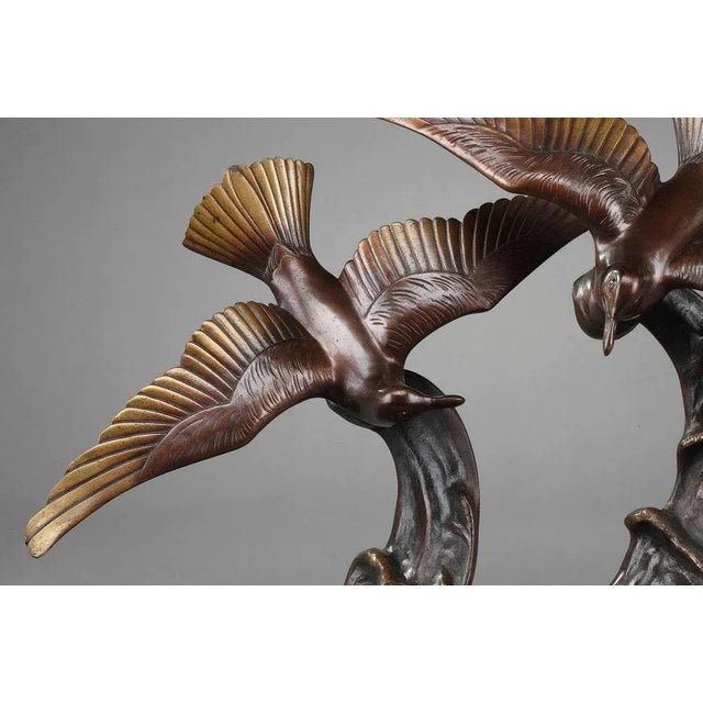 Art deco-period bronze statue featuring two flying gulls skimming the crest of a wave. The sculpture is set upon a black...