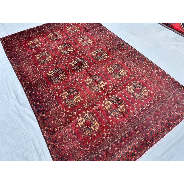 This hand-knotted Mauri Bokhara rug features bold, finely woven octagonal guls set in a neat grid across a deep madder-red...