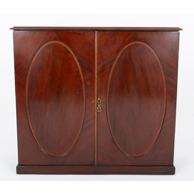 Georgian mahogany 2 door side cabinet Circa 1800 This cabinet stands upon a plinth base Featuring 2 panelled doors, each...