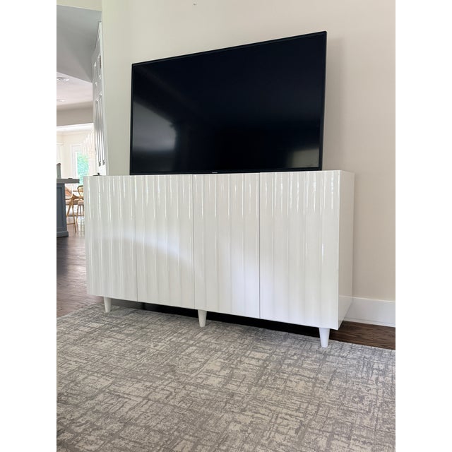 Odette Cabinet in White Lacquer A unique scalloped design conceals four doors which open to reveal ample storage. Both...