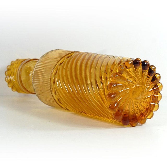 A tall, unique bottle/carafe made of pressed glass in an intense honey color. It comes from the Italian Empoli label from...