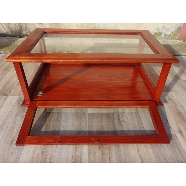 Low cabinet, designed to be placed on the floor or a table, with four legs and glass panels on five sides. The frame and...