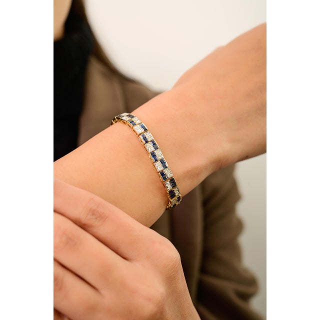This vintage-style tennis bracelet features square cut blue sapphires totaling 6.01 carats set in rich 14K yellow gold....