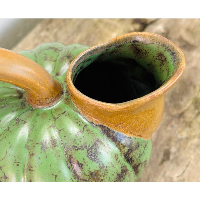 This charming and organic ceramic pitcher originates from France in the 1920s. The pitcher features a beautiful green body...