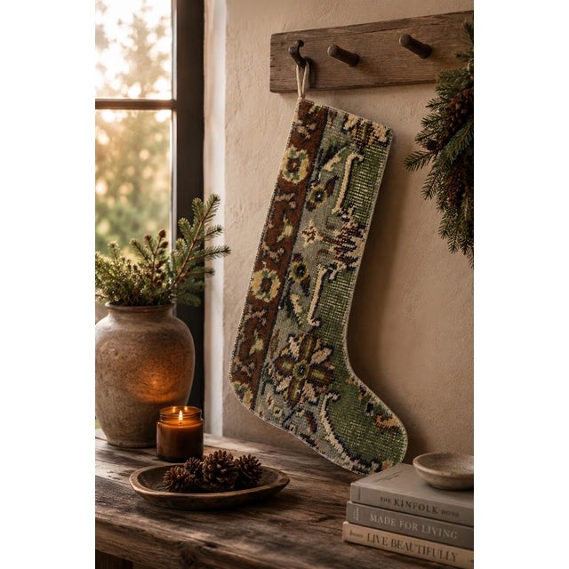 This vintage wool kilim stocking showcases an intricate floral medallion pattern in sage green, cream, and warm brown,...