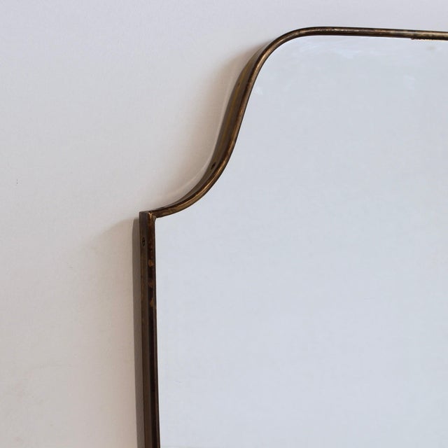 One of two identical vintage Italian wall mirrors with a brass frame (circa 1960s). The mirror is crest-shaped—classically...