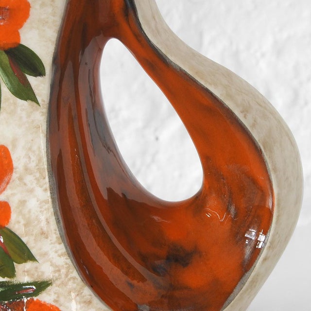 Large hand-decorated glass with orange and green flower decoration, matching orange interior, with hole on one side Signed...